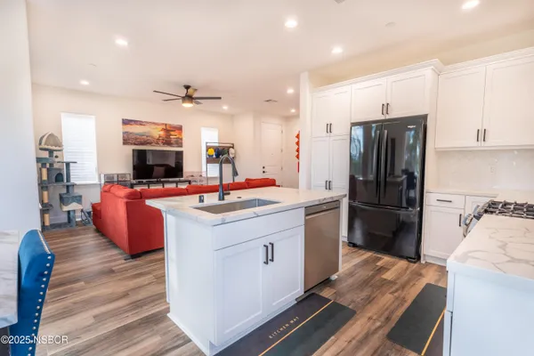 a living room with furniture a ceiling fan and a large window