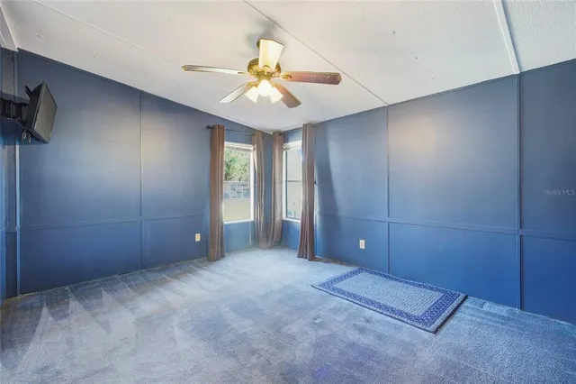 a view of a fountain in front of a house with a big yard and large trees