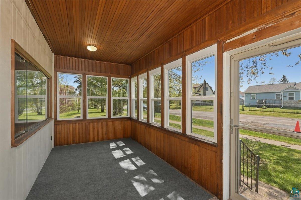 5319 East 3rd Street Superior, WI 54880 - Photo 4 of 33 Enclosed porch featuring wood-panel walls and ceiling, multiple windows, and carpet flooring