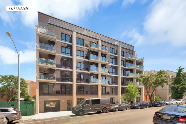 a front view of a building with lot of cars and trees