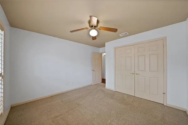an empty room with ceiling fan and window