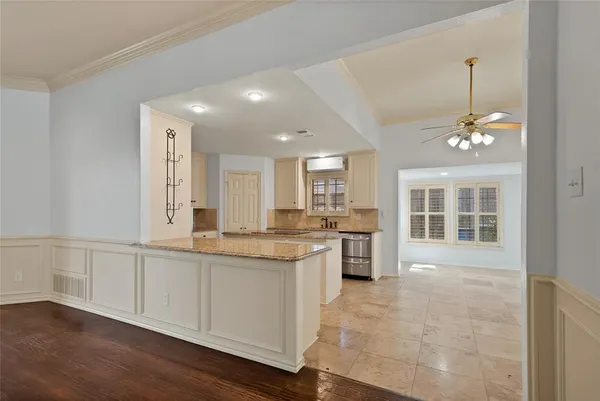 a large kitchen with granite countertop a stove and white cabinets