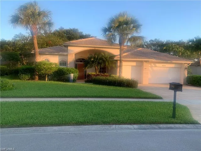a front view of a house with a yard and potted plants