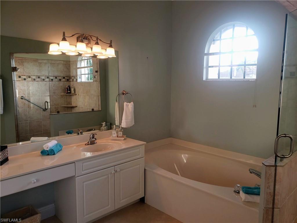 8906 Lely Island Circle Naples, FL 34113 - Photo 18 of 36 a bathroom with a tub sink and mirror