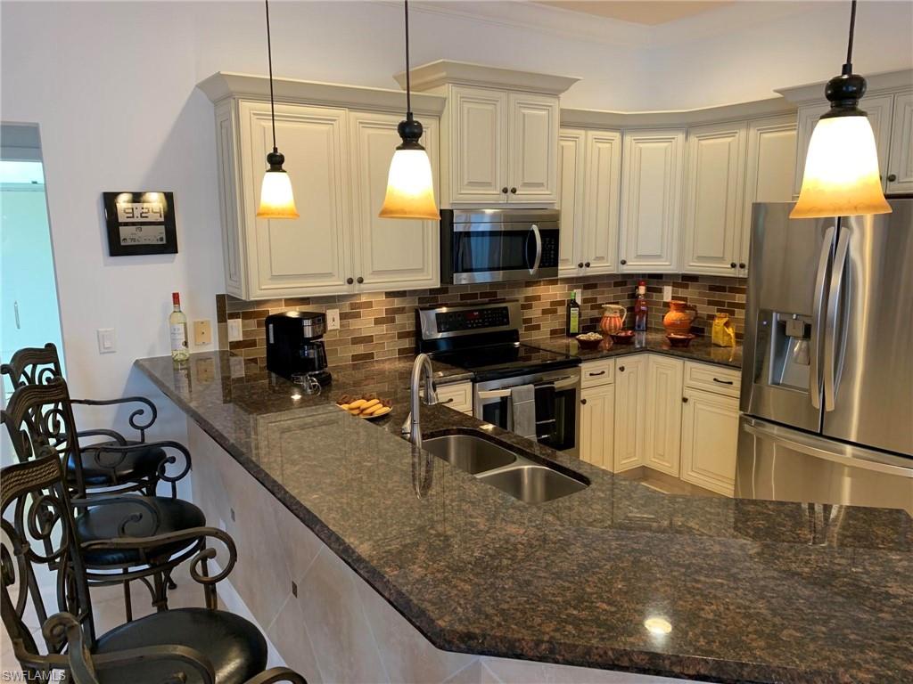 8906 Lely Island Circle Naples, FL 34113 - Photo 9 of 36 a kitchen with a sink a stove and a refrigerator