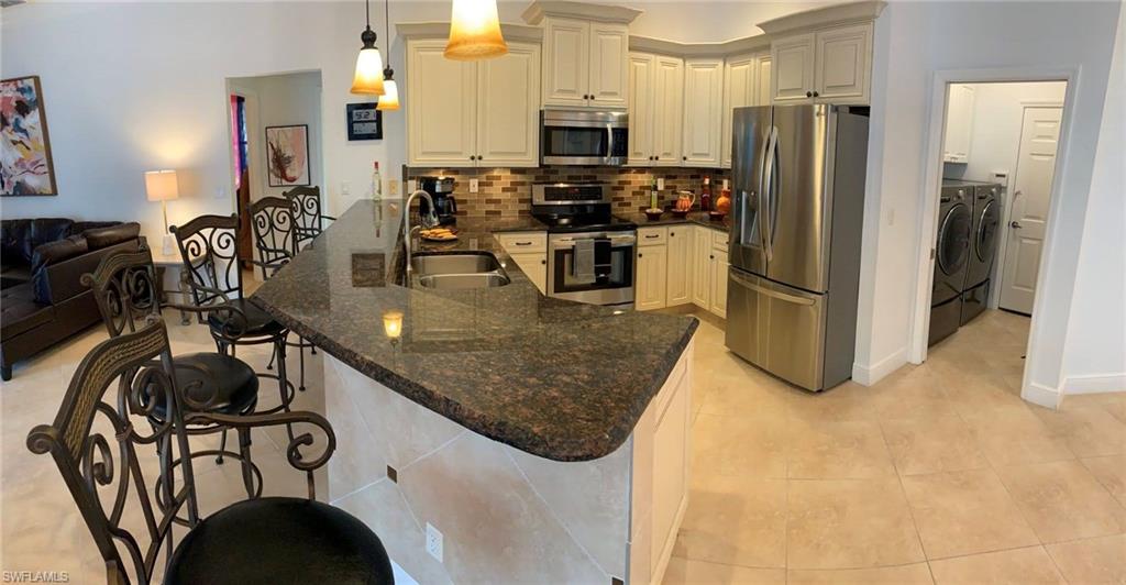 8906 Lely Island Circle Naples, FL 34113 - Photo 10 of 36 a kitchen with stainless steel appliances granite countertop a sink a stove and a refrigerator