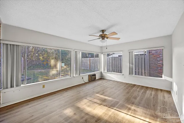 a view of an empty room with a window and wooden floor