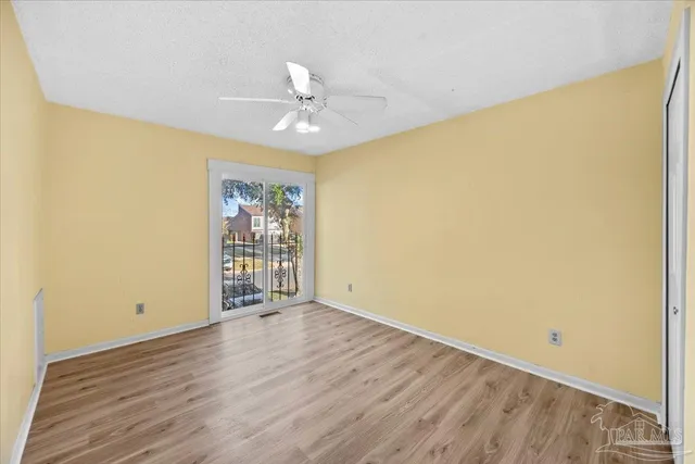 a view of a backyard with large trees and wooden fence