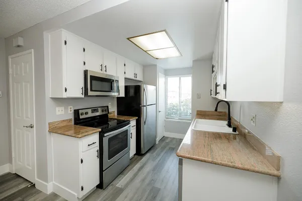 a kitchen with granite countertop a sink a stove top oven and wooden floor