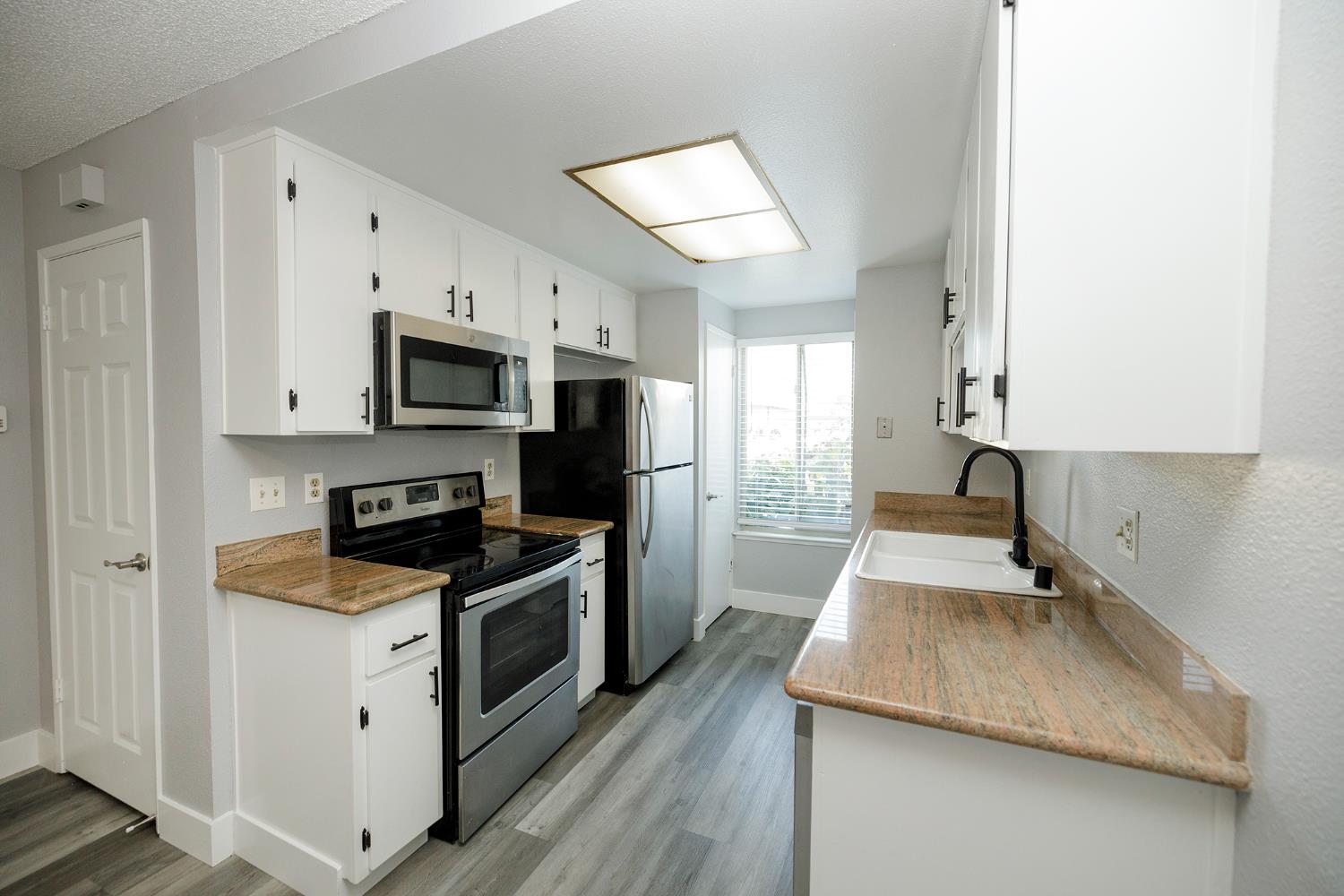 1313 Floyd Avenue, Unit 122 Modesto, CA 95355 - Photo 17 of 35 a kitchen with granite countertop a sink a stove top oven and wooden floor