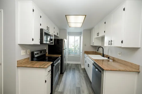 a kitchen with stainless steel appliances a sink stove refrigerator and cabinets
