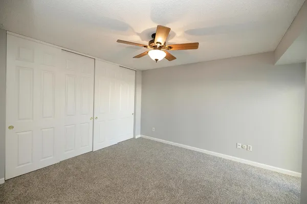 an empty room with closet and a chandelier fan