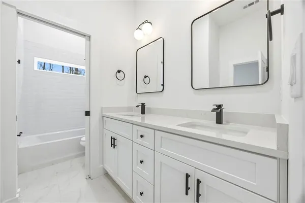a bathroom with a double vanity sink mirror and bathtub
