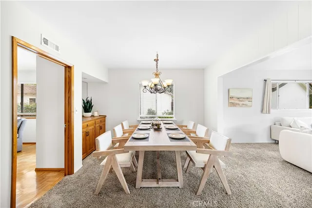 a dining room with wooden floor and a chandelier