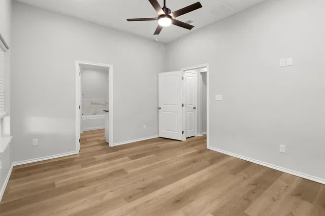 an empty room with wooden floor and a ceiling fan