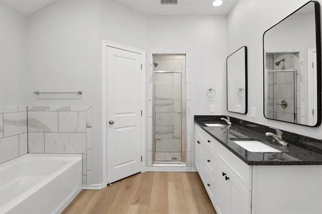 a bathroom with a granite countertop tub sink shower and mirror