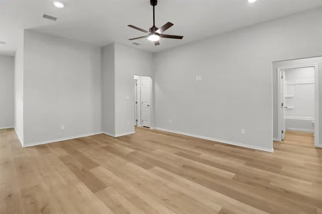 a view of a room with a ceiling fan and wooden floor