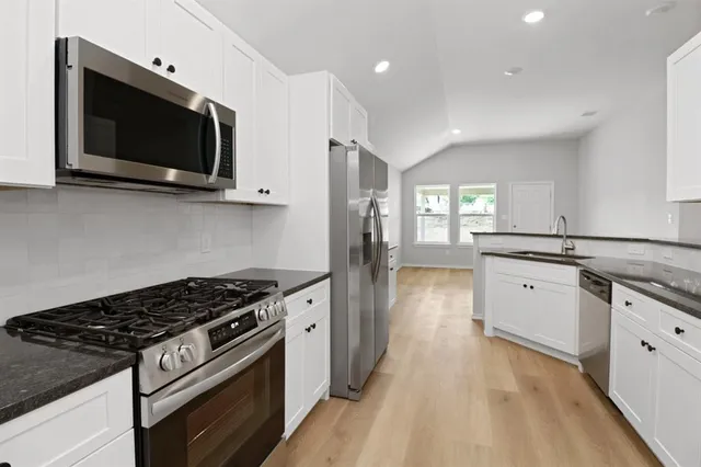 a kitchen with stainless steel appliances a sink dishwasher a stove and a microwave oven with wooden floor