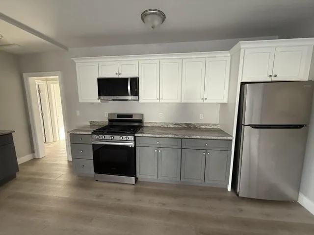 a kitchen with granite countertop a refrigerator stove top oven and sink