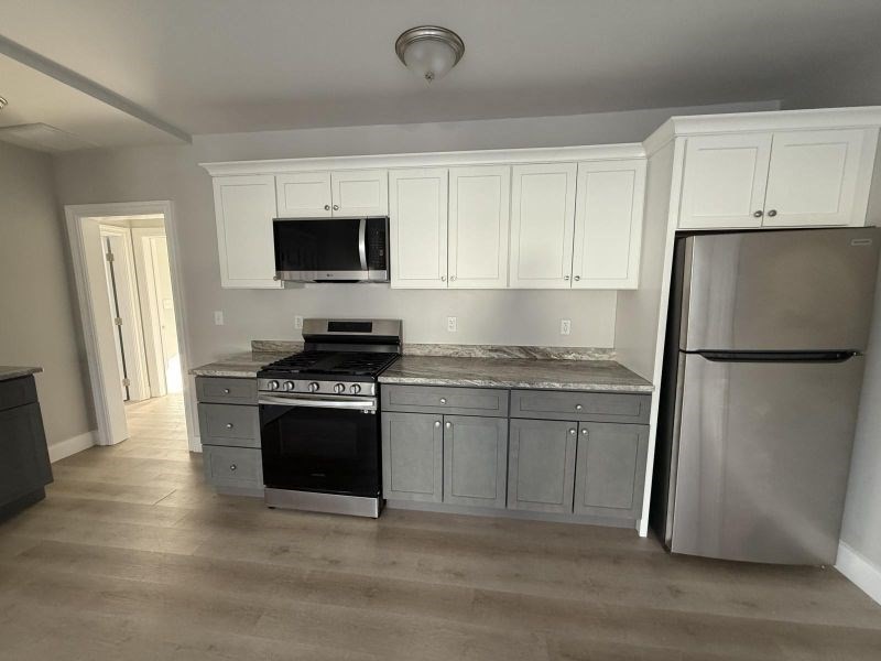 a kitchen with granite countertop a refrigerator stove top oven and sink