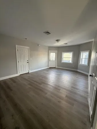 a view of empty room with window and wooden floor