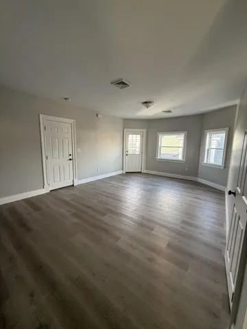a view of empty room with window and wooden floor