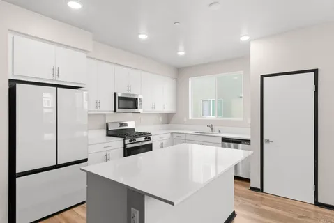 a kitchen with stainless steel appliances granite countertop a refrigerator a sink a stove a microwave and island