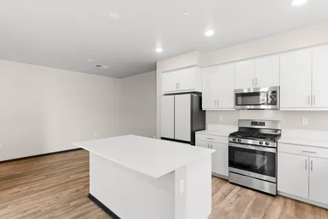 a kitchen with stainless steel appliances a refrigerator stove and white cabinets