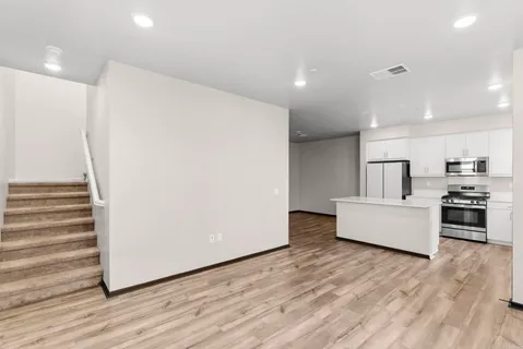 a large kitchen with stainless steel appliances a large counter top and wooden floors