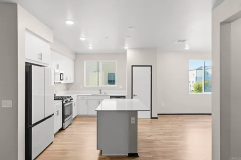 a large white kitchen with wooden floor and a refrigerator