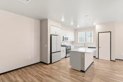 a large kitchen with a center island wooden floor and stainless steel appliances