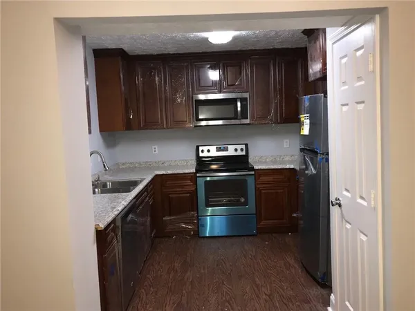 a kitchen with stainless steel appliances granite countertop wooden cabinets a stove top oven a sink and dishwasher