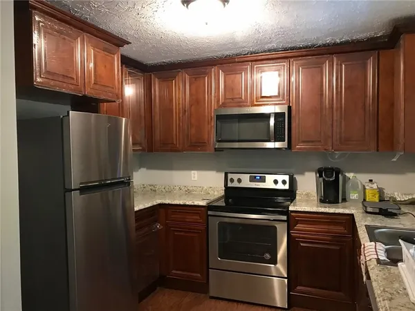 a kitchen with granite countertop a refrigerator stove and microwave