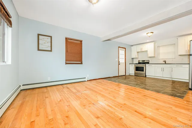 a view of an empty room with window and wooden floor