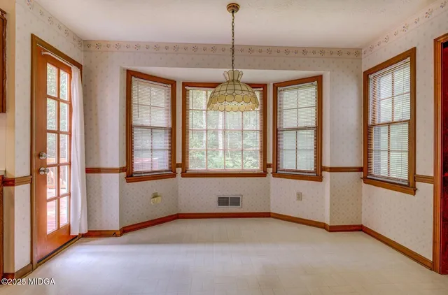 a view of an empty room with a window and chandelier fan