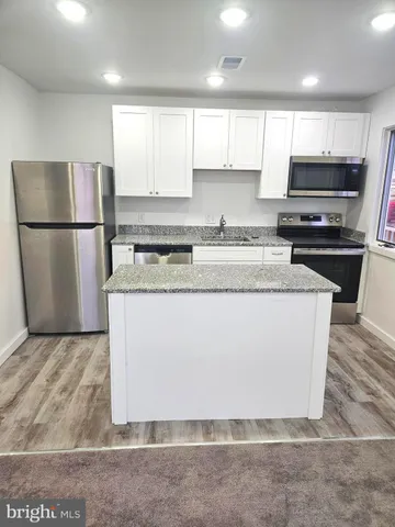 a kitchen with stainless steel appliances granite countertop a refrigerator a sink a stove a microwave and cabinets