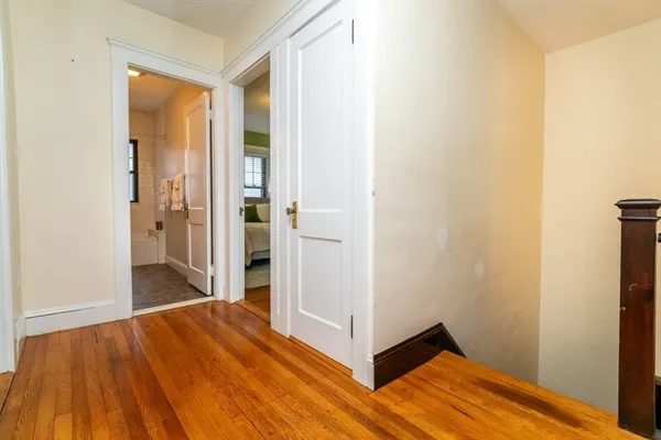a view of a hallway with wooden floor and a bathroom