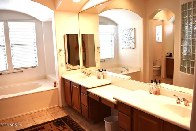 a bathroom with a sink double vanity granite tub shower and a mirror