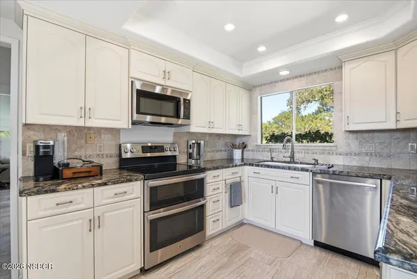 a kitchen with white cabinets and stainless steel appliances