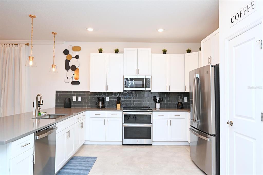 2956 Penelope Loop Kissimmee, FL 34746 - Photo 24 of 94 a kitchen with stainless steel appliances a refrigerator sink and cabinets