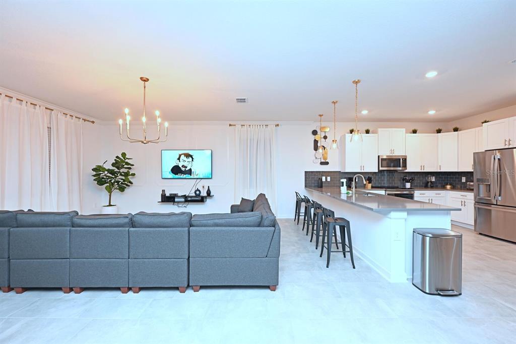 2956 Penelope Loop Kissimmee, FL 34746 - Photo 26 of 94 a living room with furniture a chandelier and kitchen view