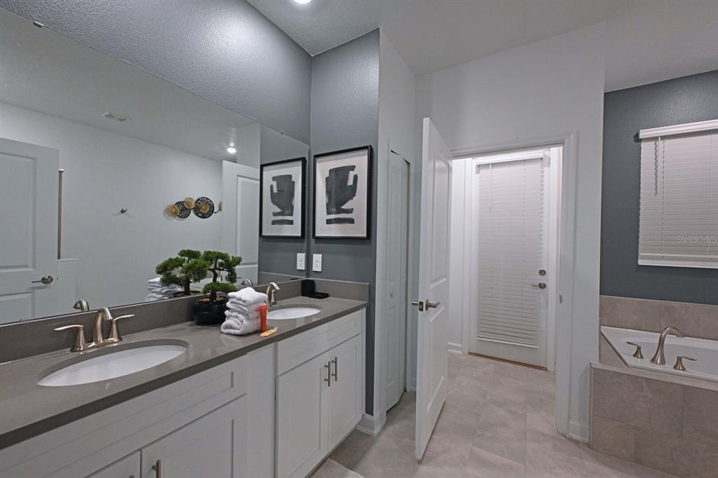 2956 Penelope Loop Kissimmee, FL 34746 - Photo 33 of 94 a bathroom with a granite countertop sink mirror and vanity