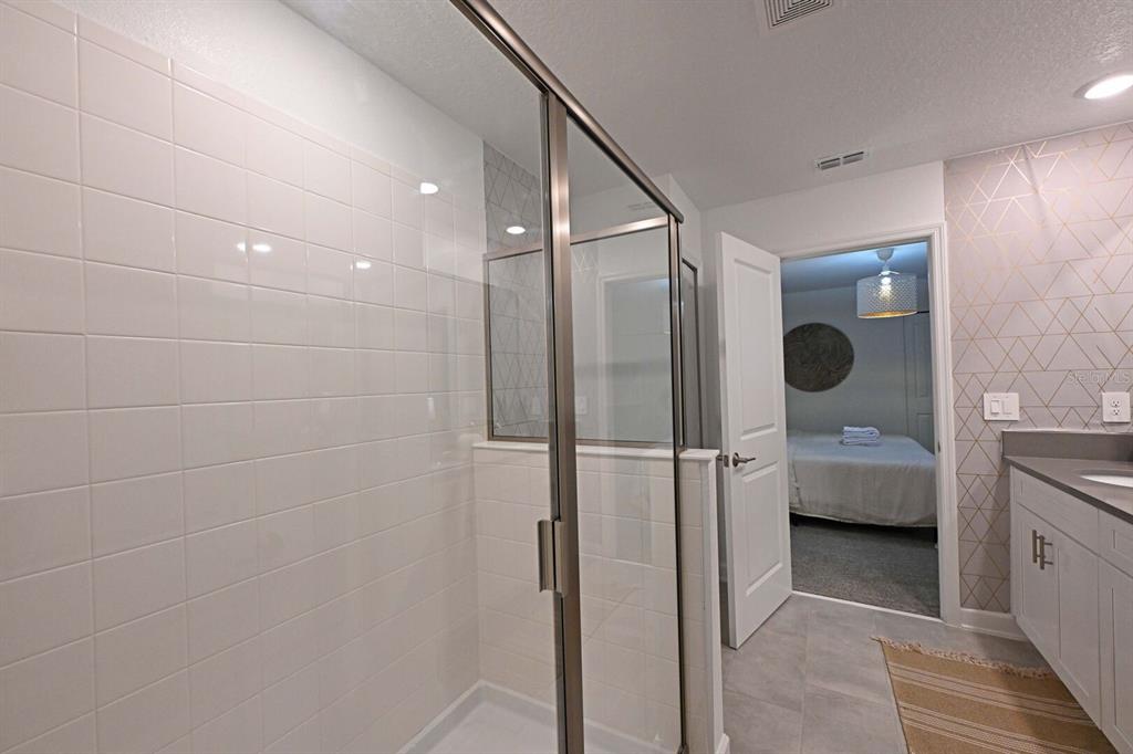 2956 Penelope Loop Kissimmee, FL 34746 - Photo 73 of 94 a bathroom with a glass door shower a sink and a mirror