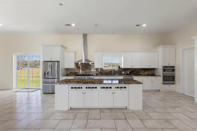 a kitchen with stainless steel appliances kitchen island granite countertop a stove and a sink