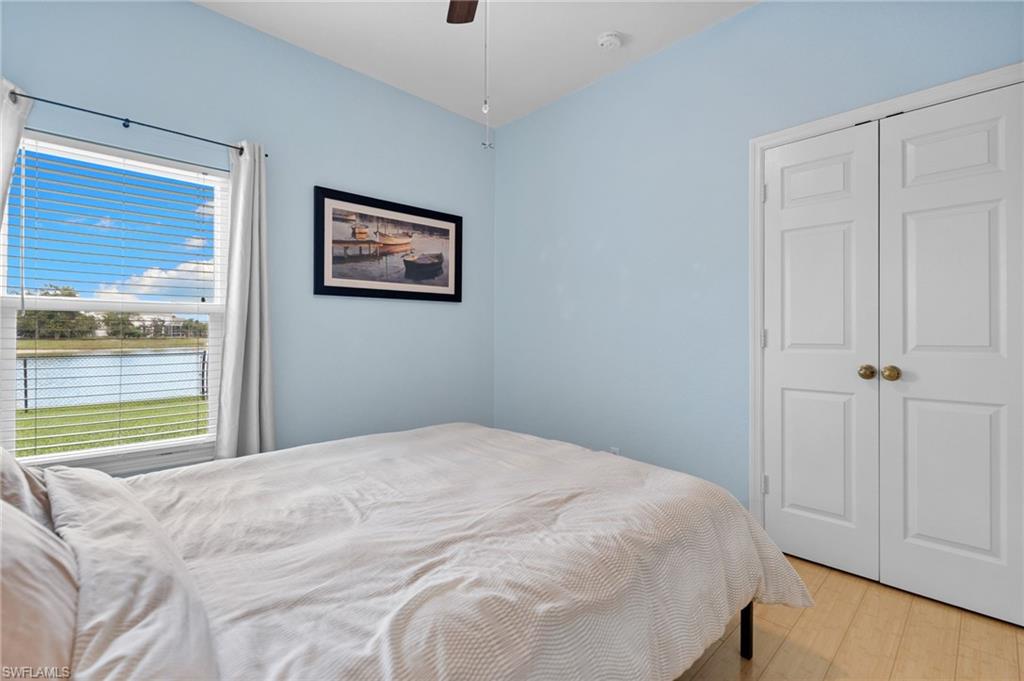 2780 Orange Grove Trail Naples, FL 34120 - Photo 18 of 29 Bedroom featuring light wood-style flooring, a water view, a ceiling fan, and a closet