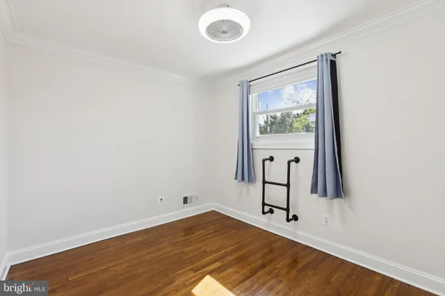 a view of an empty room with window and wooden floor