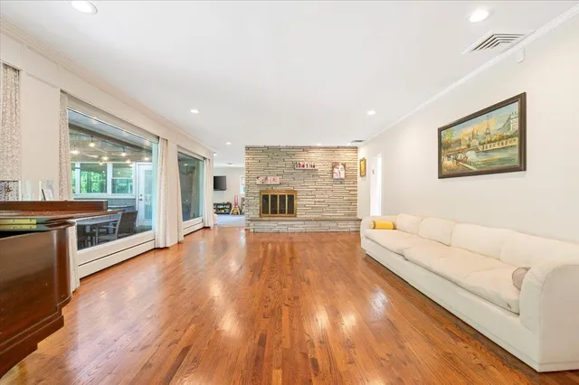 a living room with stainless steel appliances furniture a large window and a wooden floor