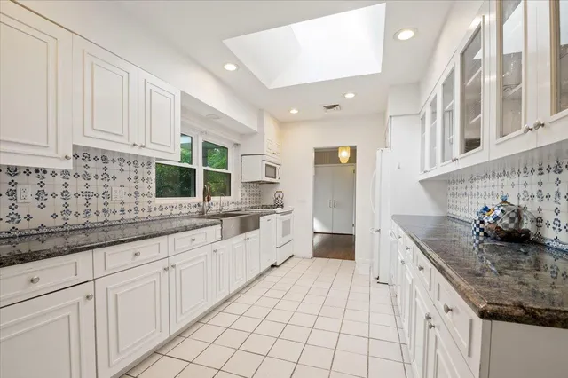 a kitchen with granite countertop a sink and white cabinets