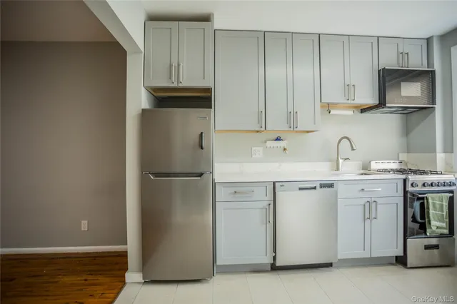 a kitchen with stainless steel appliances granite countertop a refrigerator a stove and a sink