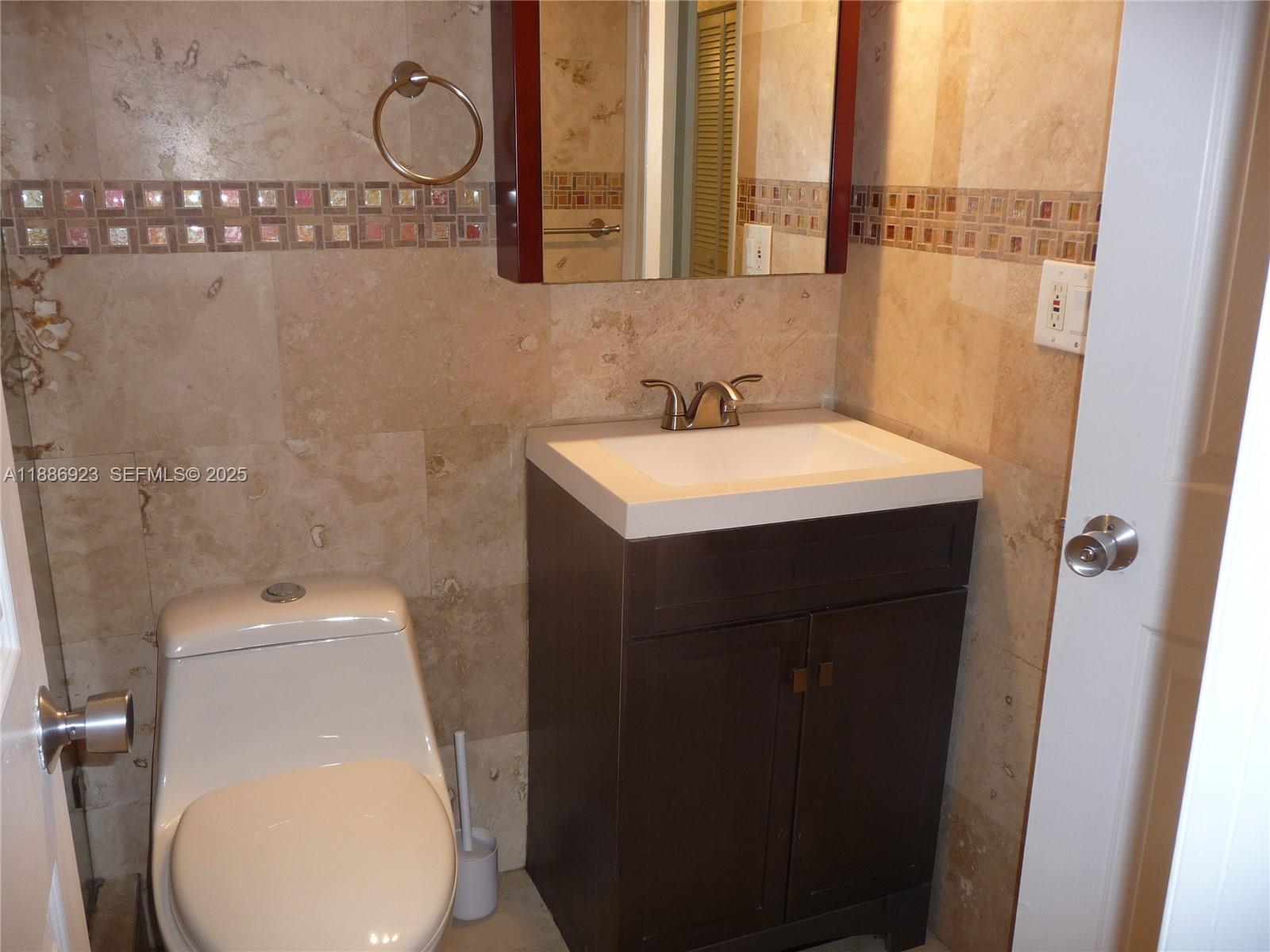 13904 Southwest 65th Terrace, Unit 8 Miami, FL 33183 - Photo 16 of 24 a bathroom with a toilet a sink and a mirror